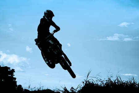 Status of silhouate motocross jumping over the amber light of sunset background.の写真素材