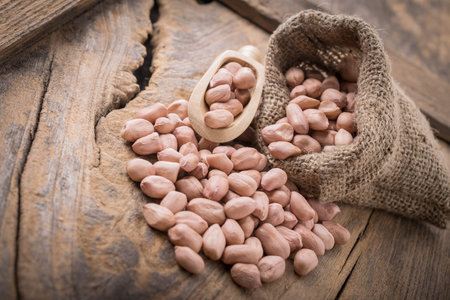 Peanut in sacks on the wooden background.