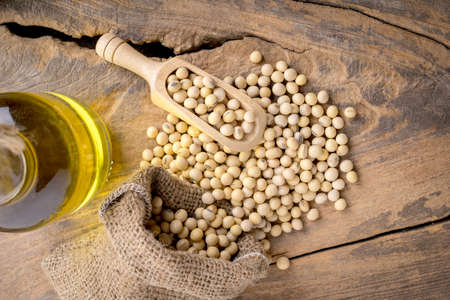 closeup is some soybeans with wooden spoon with wooden backgroundの写真素材