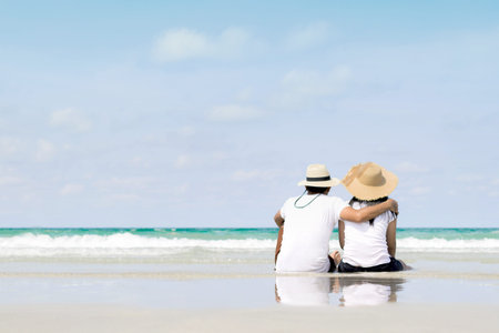 Young family sitting on warm sand by a sea and looking to somewhere
