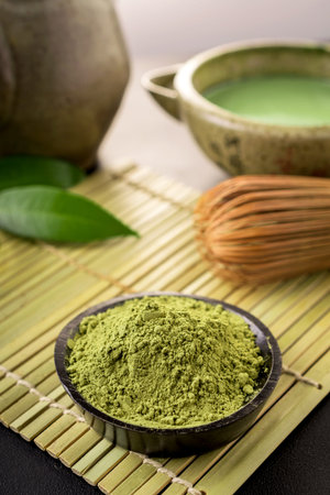 Matcha fine powdered green tea on back background.