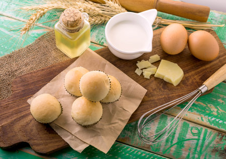 Homemade bread, milk and ripe ears of rye on a wooden background