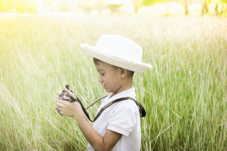 Little boy with a camera in the field, Sunsetの写真素材