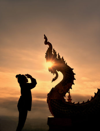 Silhouette women and Naga statue Thai dragon with sunlight