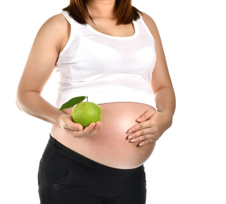 close up of pregnant woman holding green apple on white background.の写真素材