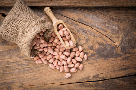 Peanut in sacks on the wooden background.の写真素材