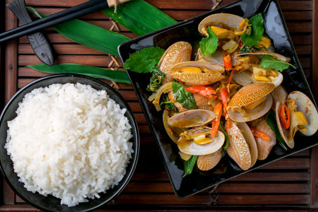 Stir fried clams with chili paste and basil leafs on wooden