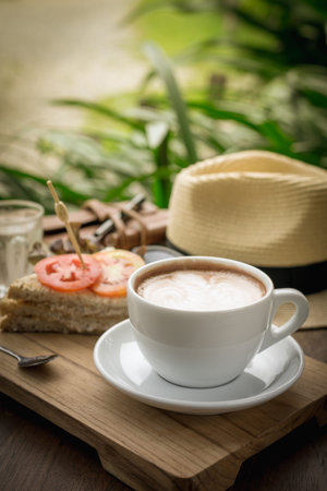 Coffee cup and sandwiches on a wooden table.