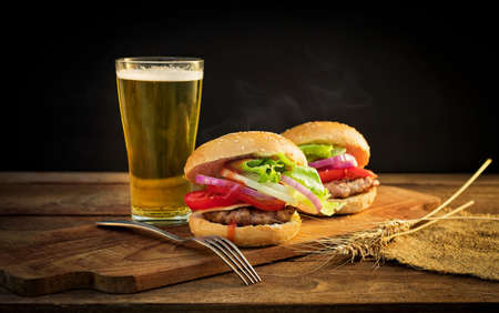 Closeup of fresh burger and a cold beer on woodenの写真素材