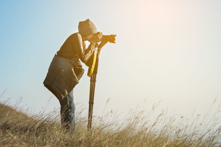 young man taking photos in mountain valley with dslr camera