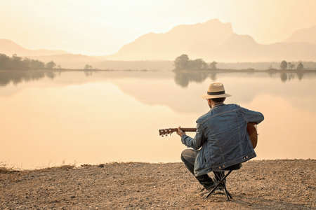 The young man guitarist The nature of the resevoir in the early morning.の写真素材