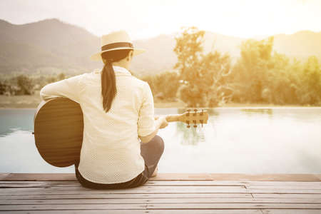 Woman playing guitar on the swimming pool.の写真素材