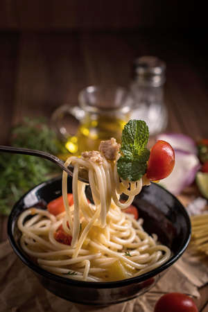 Italian spaghetti on rustic wooden table. Mediterranean cuisine with pasta ingredients- bolognese sauce, olive oil, basil and tomato.の写真素材