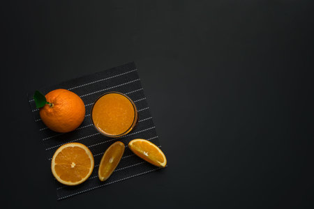 orange juice with fresh sliced orange on dark stone background