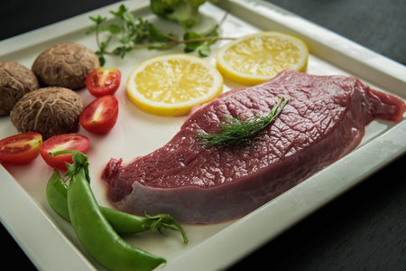 Raw steaks of veal,prepared for roasting, steak meat with salad on a black wooden background