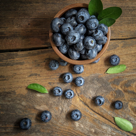 fresh bilberries or blueberries in small wooden bowls on a rustic table, selective focusの写真素材