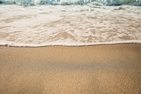 Background soft wave of Sea with foam on sandy beach, copy space.