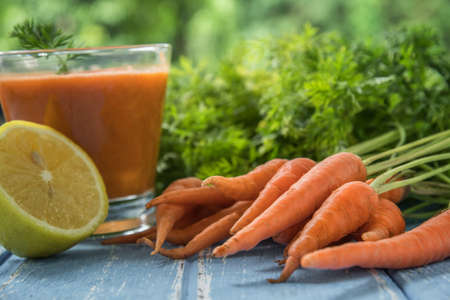 Fresh carrot juice in glasses on rustic wooden table. Natural healthy drink. Selective focus.の写真素材