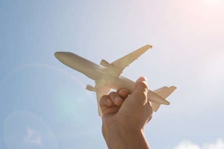 Airplane model in hand on sunny sky. Concepts of travel, transportation, transport, dreaming about holidaysの写真素材