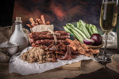 Champagne with delicious pieces of sliced ham, sausage, tomatoes, salad and vegetable - Meat platter with selection - Cutting sausage and cured meat, still life.の写真素材