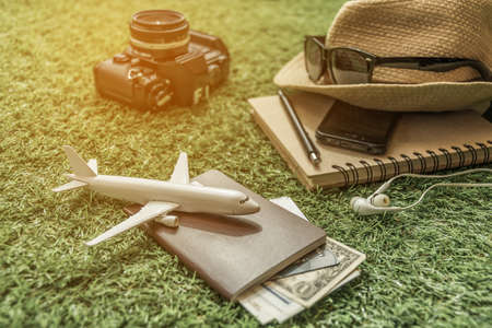 Tourist travel planning concept on grass with passport, airplane, camera,hat and sunglasses. Travel Conceptの写真素材