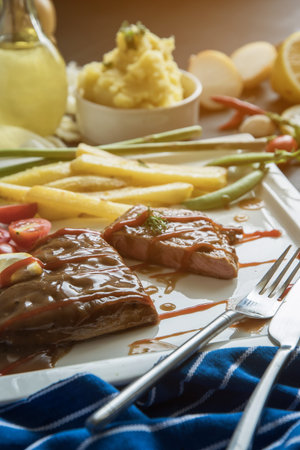 steak with vegetables, fries and barbecue sauce in a bowlの写真素材