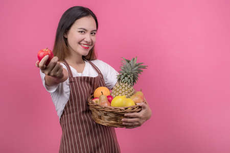 Portrait of happy young woman asian holding fruits basket while standing at studio, healthy life conceptの写真素材