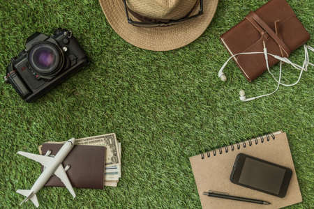 Tourist travel planning concept on grass with passport, airplane, camera,hat and sunglasses. Travel Conceptの写真素材