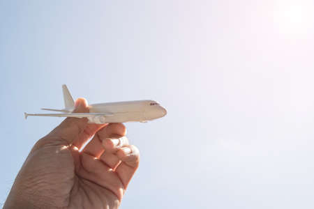 Airplane model in hand on sunny sky. Concepts of travel, transportation, transport, dreaming about holidaysの写真素材