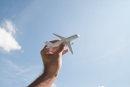 Airplane model in hand on sunny sky. Concepts of travel, transportation, transport, dreaming about...