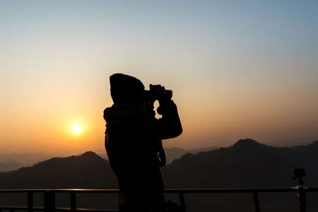 Silhouette of a photographer who was happy to shoot in the morning, a beautiful nature の写真素材
