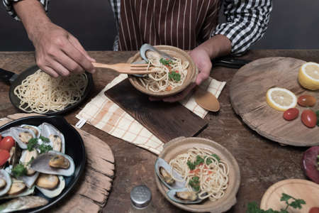 Handsome bearded cheef cook prepairing spaghetti on a kitchen, Chef cooks mealの写真素材