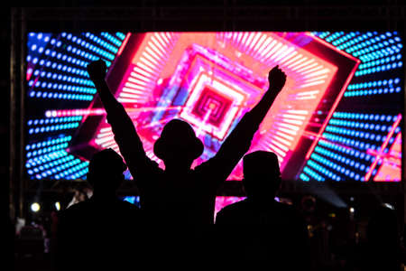silhouettes of concert crowd in front of bright stage lights.の写真素材