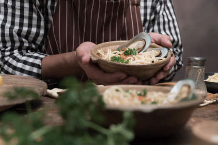 Handsome bearded cheef cook prepairing spaghetti on a kitchen, Chef cooks mealの写真素材