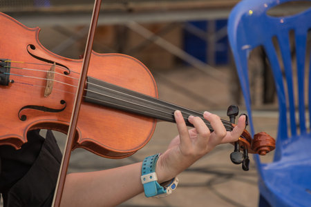 Violin in the hands of a musician in the orchestra closeup.