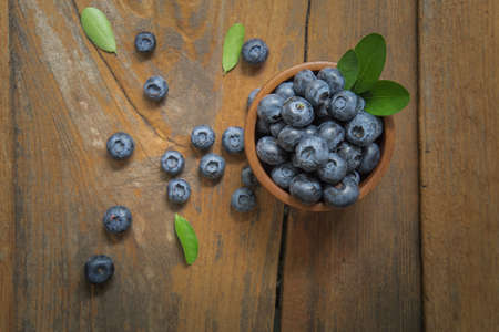 fresh bilberries or blueberries in small wooden bowls on a rustic table, selective focusの写真素材