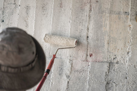 Young man clean the walls by painting white over the old cement wall, Thailand.の写真素材
