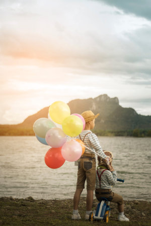 Happy boy and brother with balloons, plays with colored balloons on the beach having great holidays time on summer. Lifestyle, vacation, happiness, joy conceptの写真素材