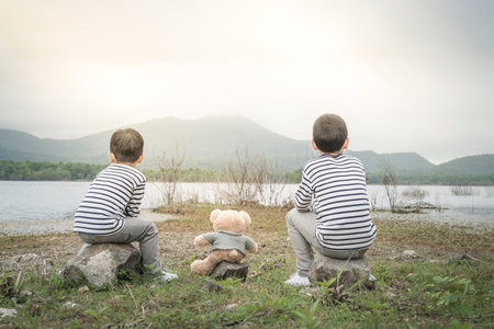 child asian with teddy bear sitting site the reservoir is the background.Thailand.の写真素材