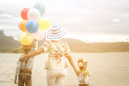 Happy family holding colorful balloons outdoor on the beach having great holidays time on summer. Lifestyle, vacation, happiness, joy conceptの写真素材