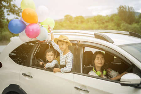 Happy family holding colorful balloons outdoor on the car having great holidays time on summer. Lifestyle, vacation, happiness, joy conceptの写真素材