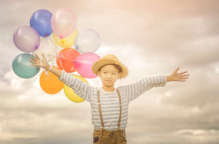 Happy boy plays with colored balloons on the beach having great holidays time on summer. Lifestyle, vacation, happiness, joy conceptの写真素材