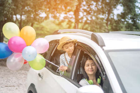 Happy family holding colorful balloons outdoor on the car having great holidays time on summer. Lifestyle, vacation, happiness, joy conceptの写真素材