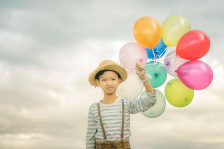 Happy boy plays with colored balloons on the beach having great holidays time on summer. Lifestyle, vacation, happiness, joy conceptの写真素材