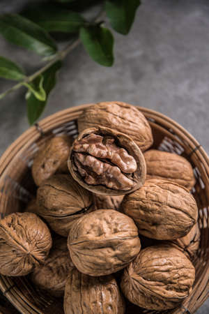 Walnuts in wooden bowl. Whole walnut on  table with green leavesの写真素材