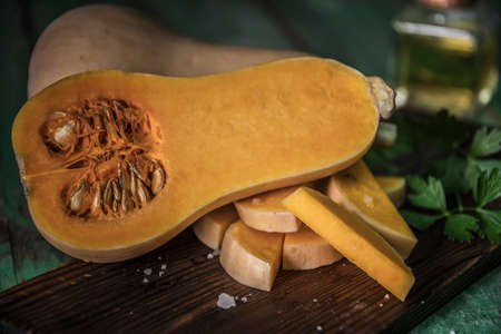 butternut squash over old wood background, Pumpkin pieces, harvest, fall. Dark brown background. Cooking in autumn. Healthy food.の写真素材
