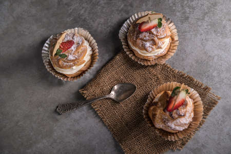 Homemade profiteroles with cream, strawberries and mint. Dessert for gourmets. Selective focusの写真素材