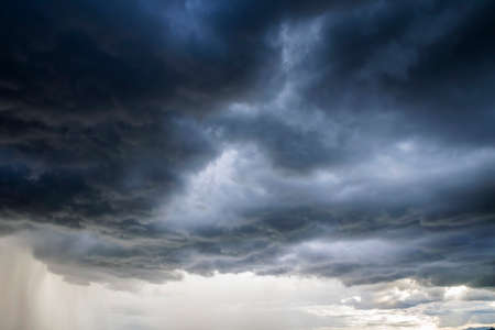 Light in the Dark and Dramatic Storm Clouds background, Black cumulus clouds before the beginning of a strong stormの写真素材