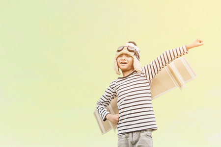 Happy child playing with toy wings against summer sky background. Retro toned
