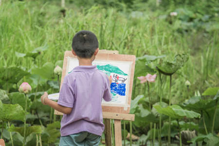Child drawing near the water lilies pondの写真素材